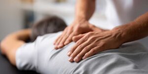 Patient in comfortable clothing discusses back pain with a chiropractor during an initial examination.