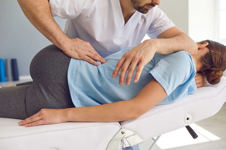 A chiropractor checks spinal alignment for an adult patient in a calm, well-lit clinic room.